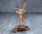 Wooden sculpture of a dragonfly and mushrooms on a natural wood base against a gray background