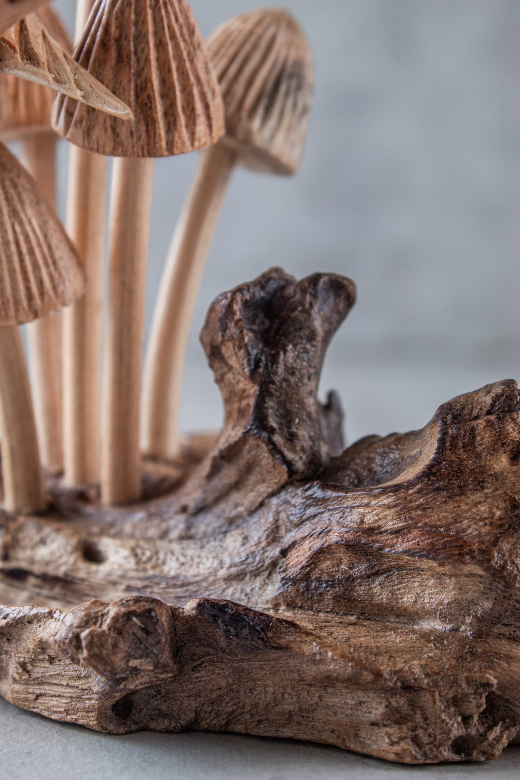Wooden mushroom figurines on a natural wood base with a blurred background