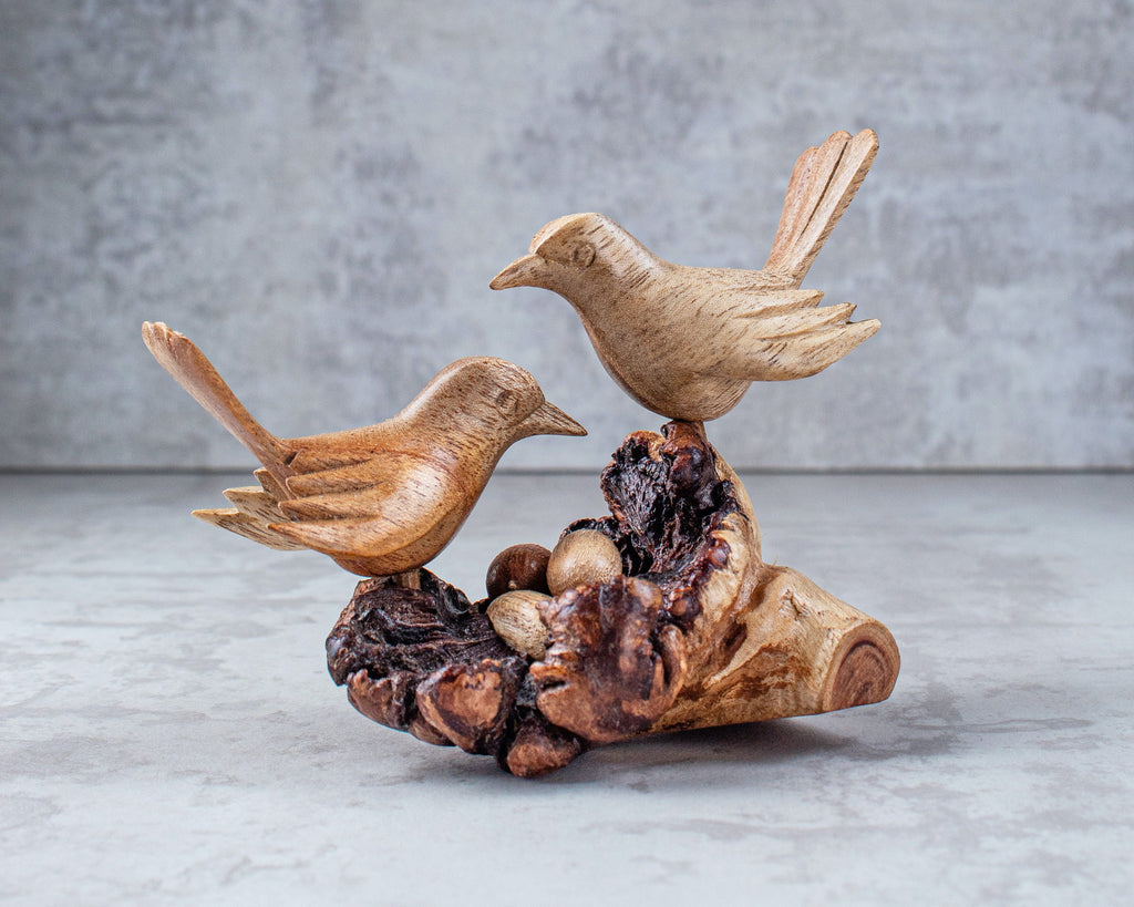 Wooden bird sculpture on a natural wood base with a gray background
