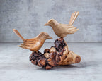 Wooden bird sculpture on a natural wood base with a gray background
