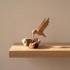 Hand-carved wooden hummingbird building nest sculpture