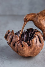 Wooden bird pecking at a nest on a gray surface