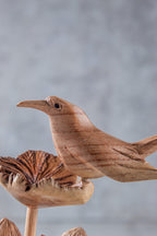 Wooden bird sculpture on a branch with a blurred background
