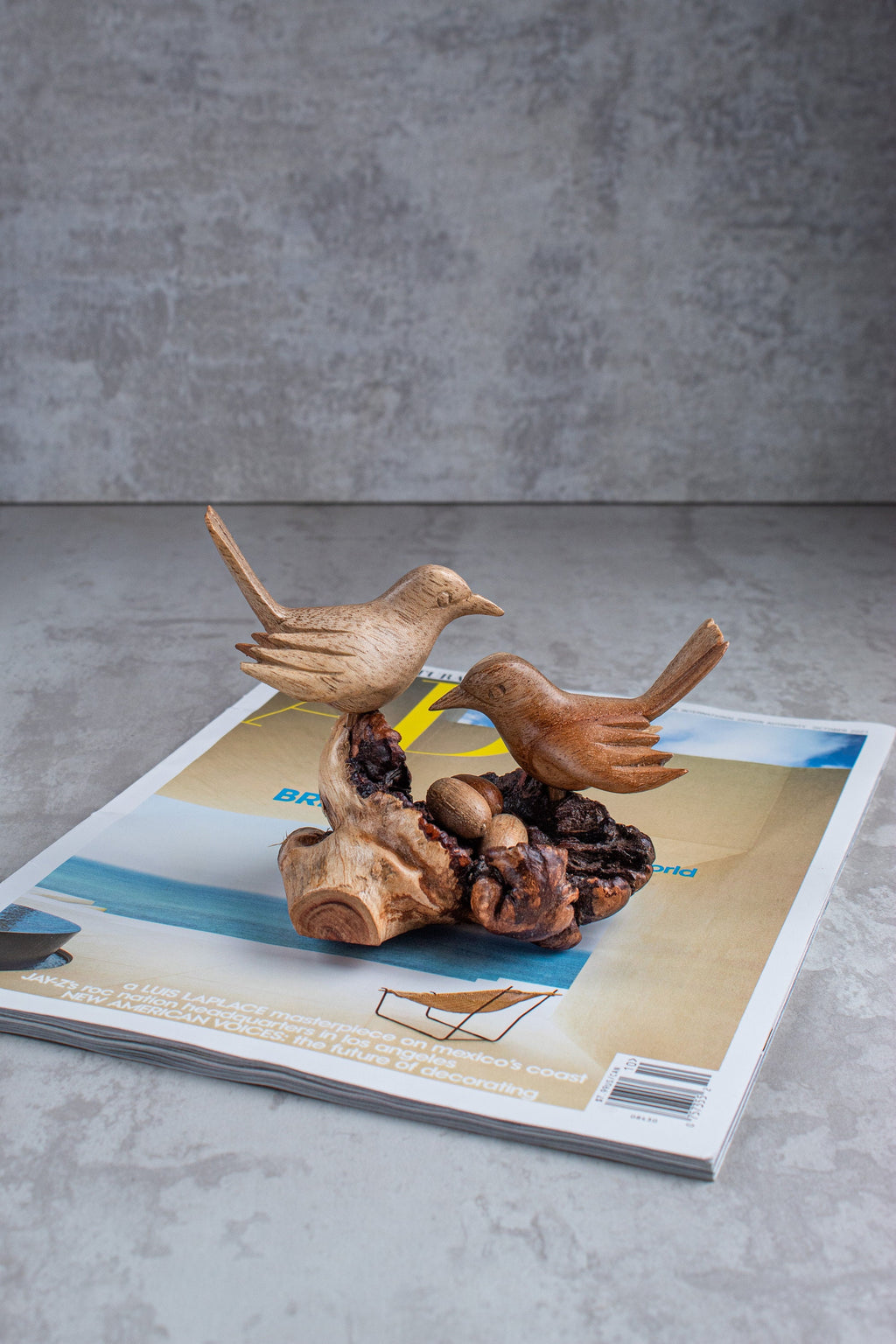 Wooden bird sculpture on a magazine with a gray background