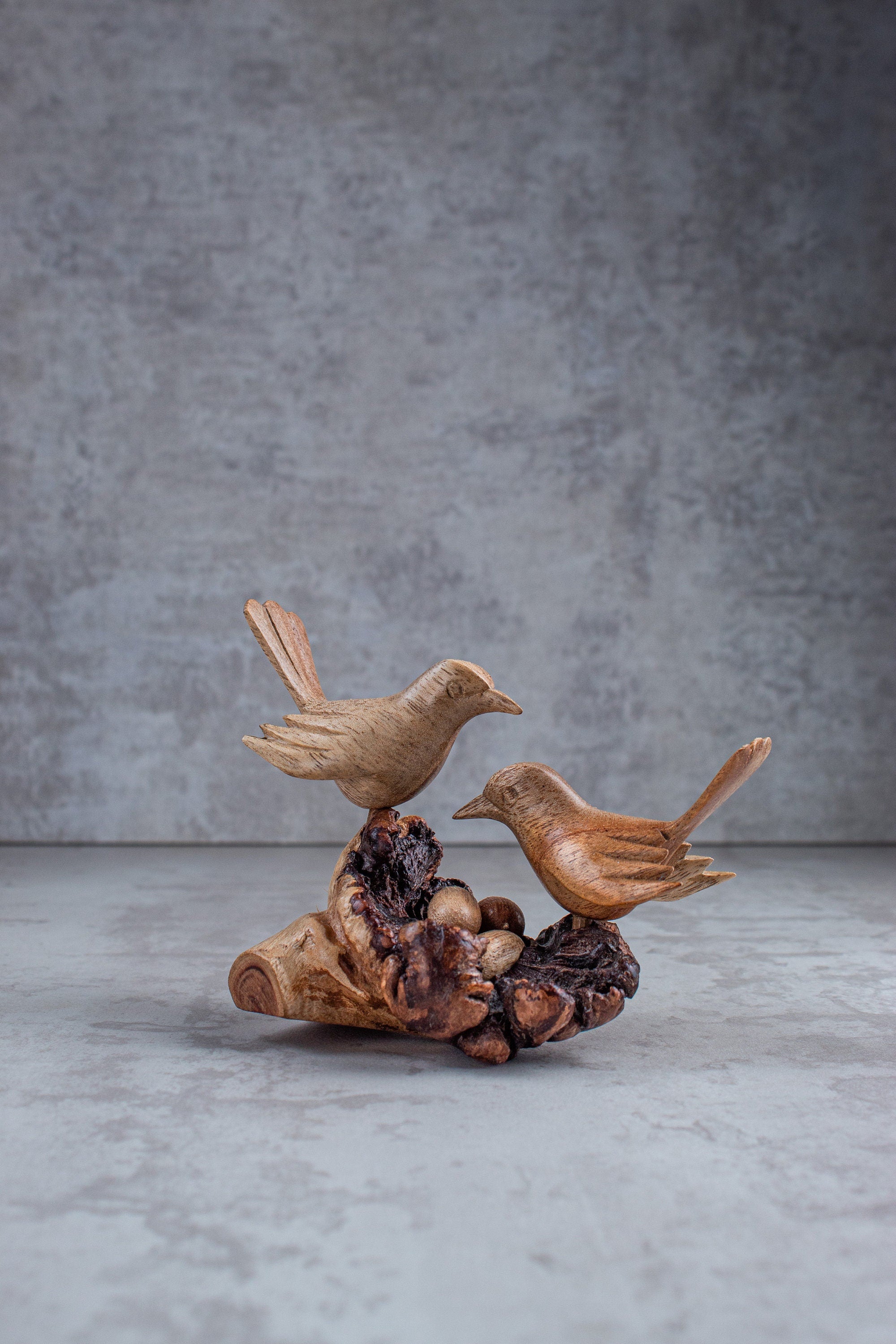 Wooden bird sculpture on a textured surface with a gray background