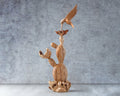 Wooden sculpture of a cactus with a bird on top against a gray background