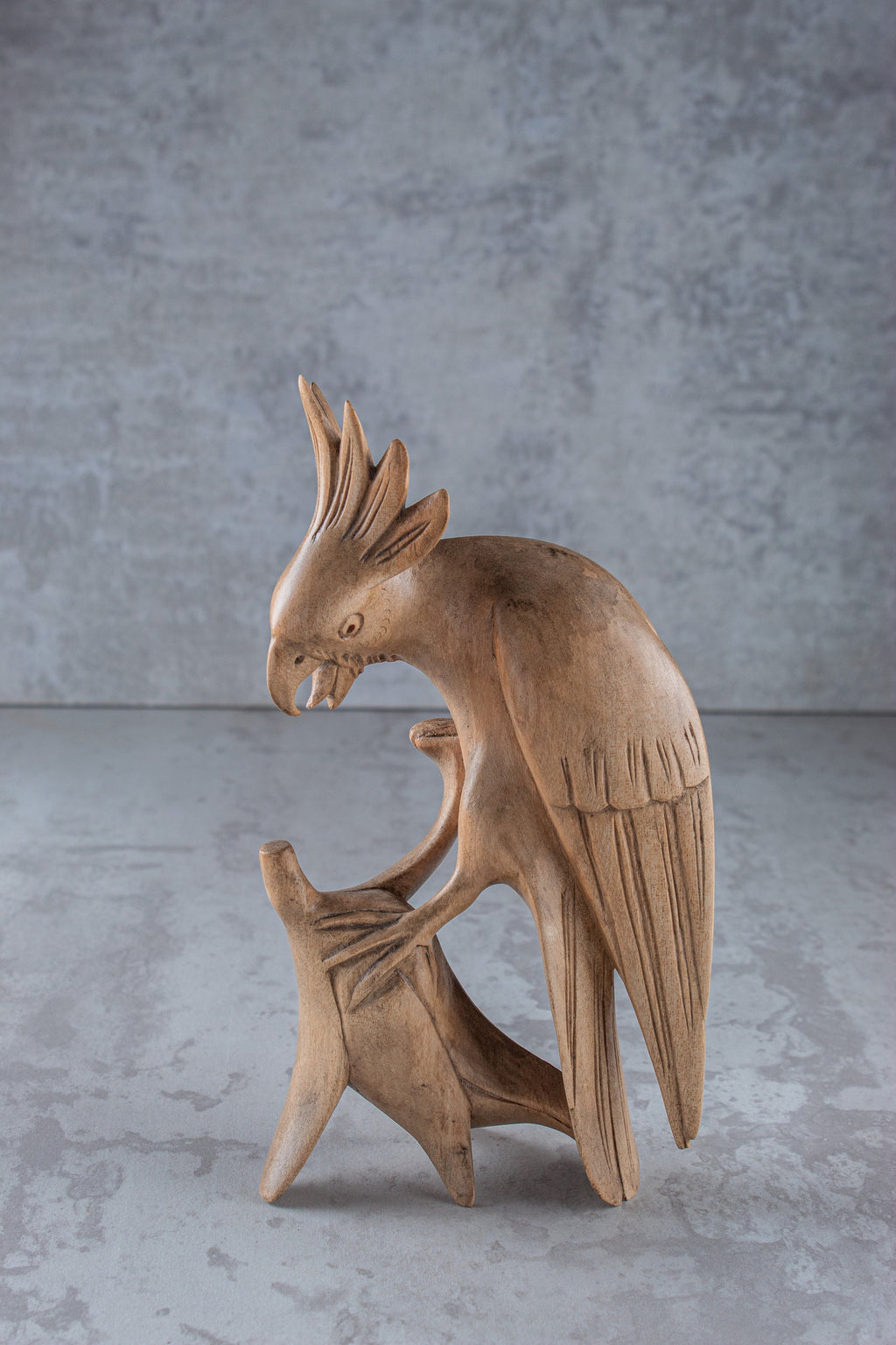 Wooden sculpture of a parrot on a gray background